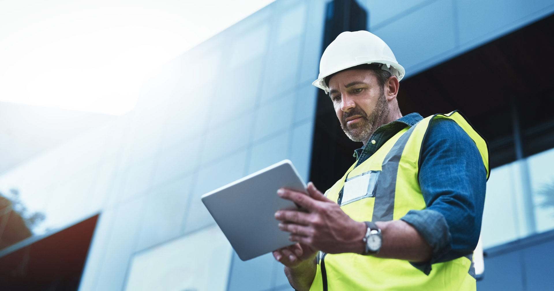 A construction worker using a tablet on site is slowed down by outdated technology.